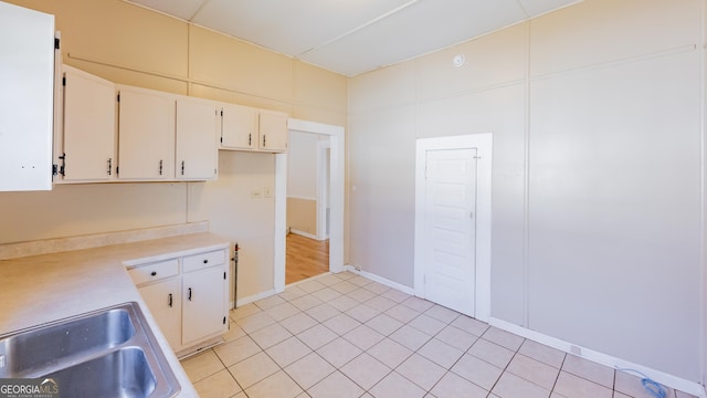 kitchen featuring white cabinets, light tile patterned flooring, and sink