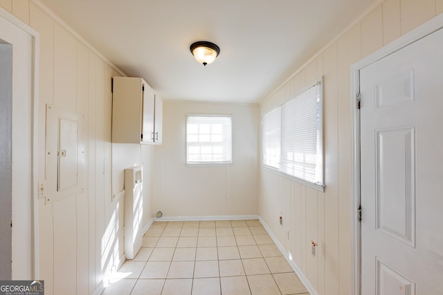 laundry area featuring light tile patterned flooring, cabinets, crown molding, and electric panel