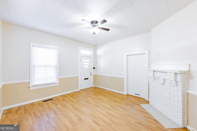 unfurnished living room featuring a fireplace, light wood-type flooring, and ceiling fan