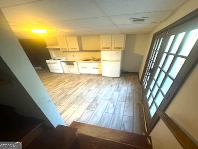 kitchen with a paneled ceiling, white refrigerator, light wood-type flooring, and a healthy amount of sunlight