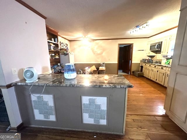 kitchen with crown molding, light hardwood / wood-style flooring, ceiling fan, dark stone countertops, and a textured ceiling