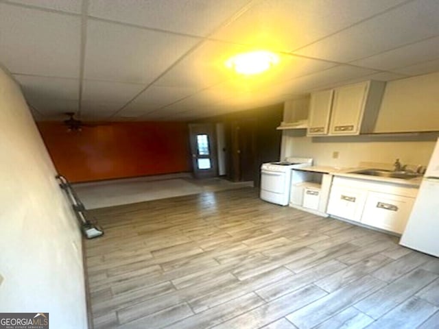 kitchen with a drop ceiling, white appliances, sink, and light hardwood / wood-style flooring