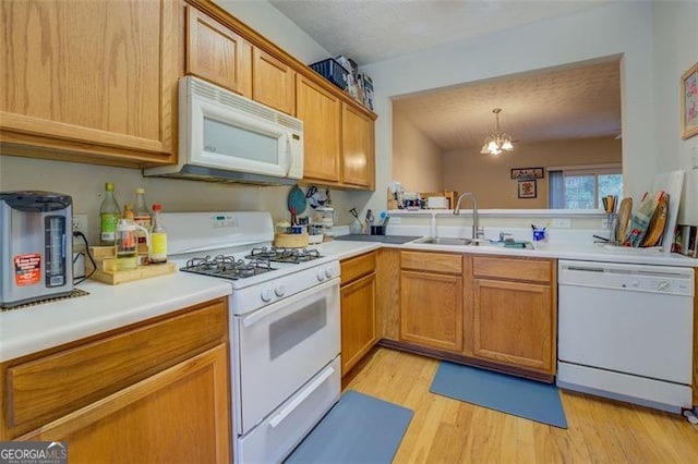 kitchen with sink, a chandelier, decorative light fixtures, white appliances, and light wood-type flooring