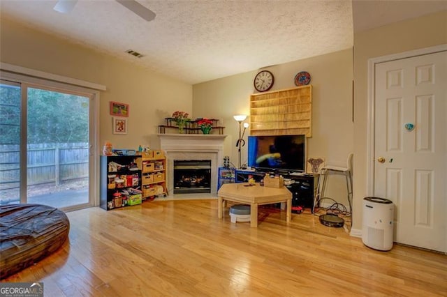 living room with ceiling fan, wood-type flooring, and a textured ceiling