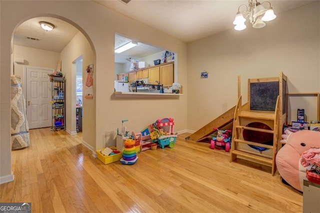 rec room with light hardwood / wood-style flooring and an inviting chandelier