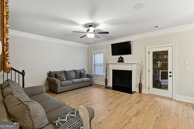 living room featuring light wood-type flooring, ceiling fan, and ornamental molding