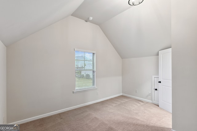 additional living space with light colored carpet and lofted ceiling