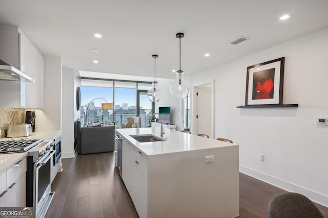 kitchen featuring appliances with stainless steel finishes, a kitchen island with sink, sink, pendant lighting, and white cabinets