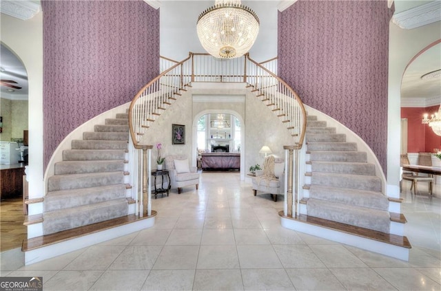 foyer featuring tile patterned flooring, ornamental molding, a towering ceiling, and a chandelier