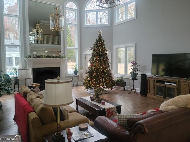 living room with light hardwood / wood-style floors, a high ceiling, and an inviting chandelier