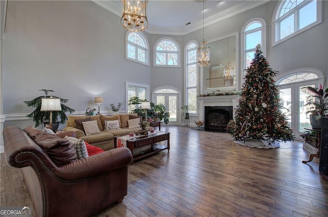 living room with a chandelier, hardwood / wood-style floors, a wealth of natural light, and a high ceiling