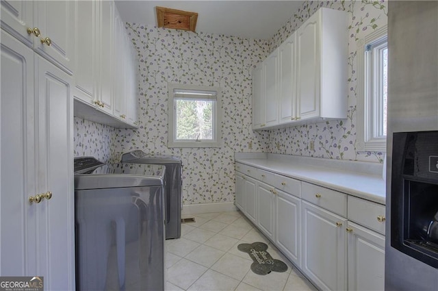 clothes washing area featuring light tile patterned flooring, cabinets, and independent washer and dryer