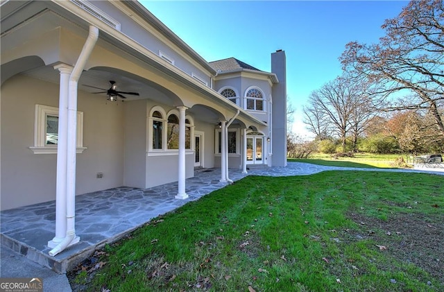 rear view of house featuring french doors, ceiling fan, and a lawn