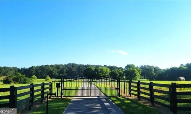 view of gate with a yard and a rural view