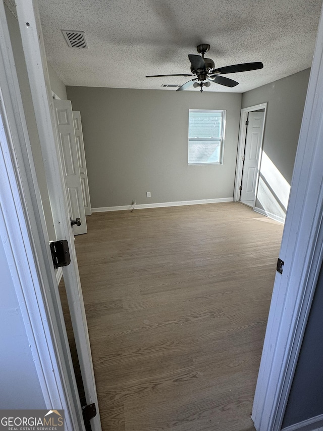 spare room with a textured ceiling, hardwood / wood-style flooring, and ceiling fan