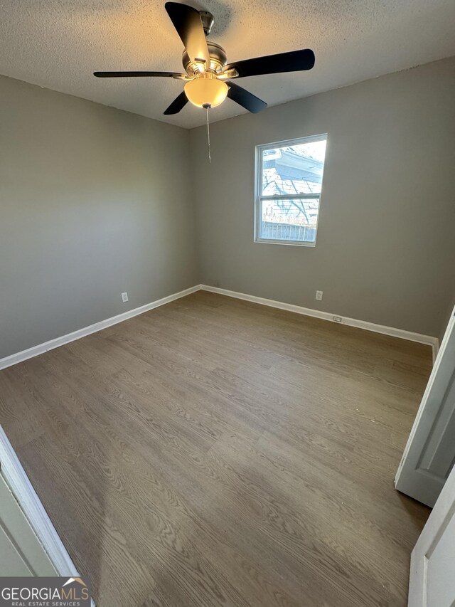 empty room featuring ceiling fan, wood-type flooring, and a textured ceiling