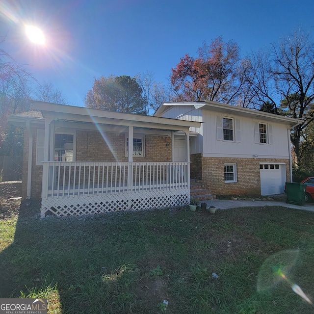 tri-level home featuring a garage, a lawn, and a porch