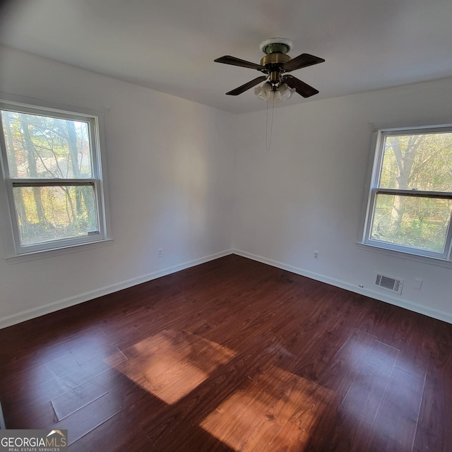 empty room with plenty of natural light, dark hardwood / wood-style floors, and ceiling fan