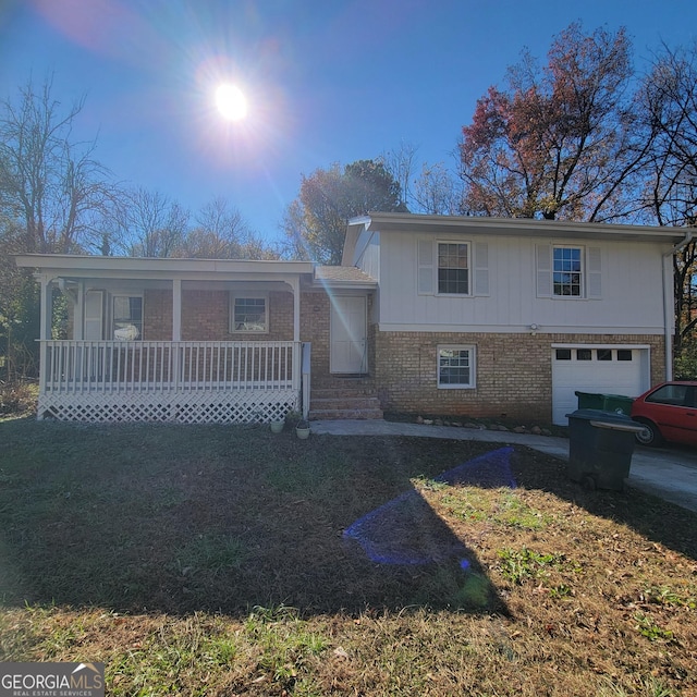 tri-level home featuring a garage, covered porch, and a front yard