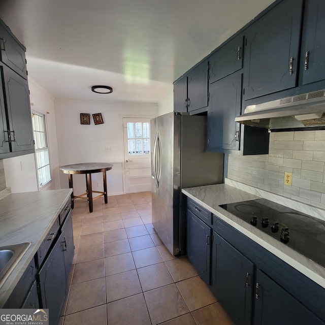 kitchen with sink, light tile patterned floors, stainless steel fridge, black electric stovetop, and decorative backsplash