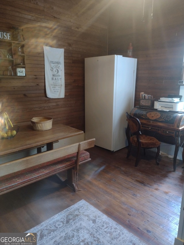 dining room featuring dark hardwood / wood-style floors and wood walls