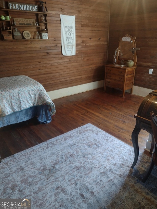 bedroom with dark hardwood / wood-style floors and wood walls