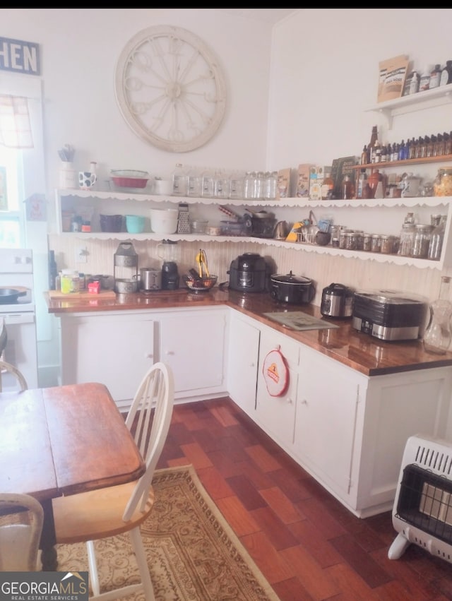 kitchen with white range, dark hardwood / wood-style floors, white cabinetry, and heating unit