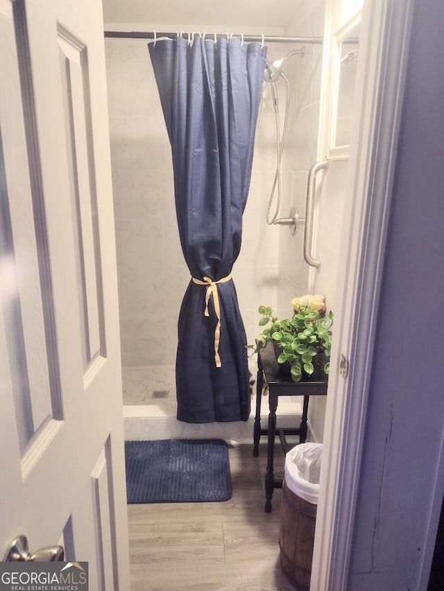 bathroom with hardwood / wood-style flooring and curtained shower