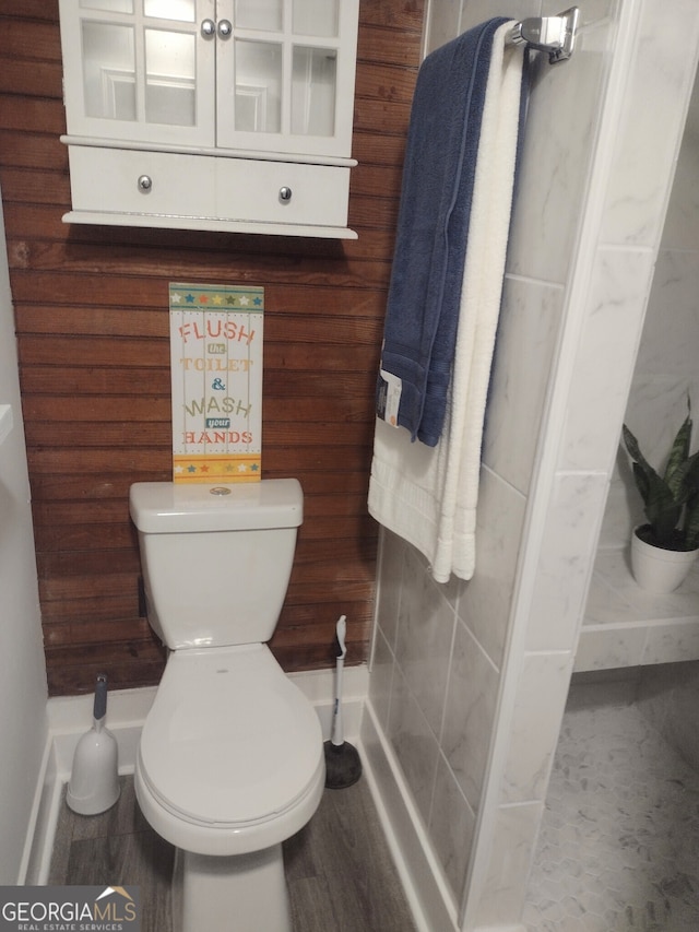 bathroom with wood walls and toilet