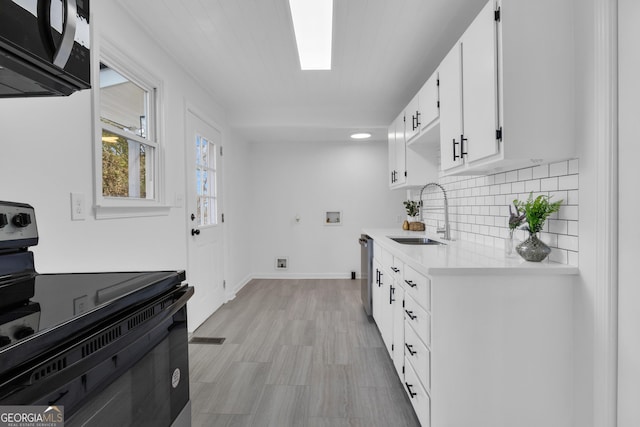 kitchen featuring dishwasher, sink, tasteful backsplash, black / electric stove, and white cabinets