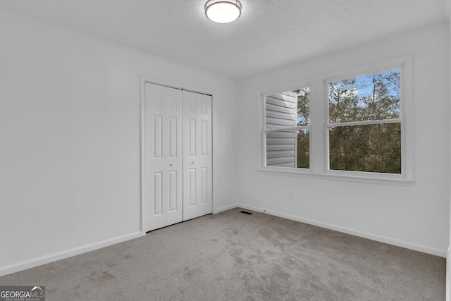 unfurnished bedroom with a textured ceiling, carpet floors, and a closet