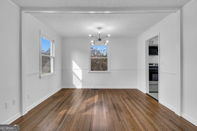 unfurnished dining area with plenty of natural light, ornamental molding, dark wood-type flooring, and an inviting chandelier