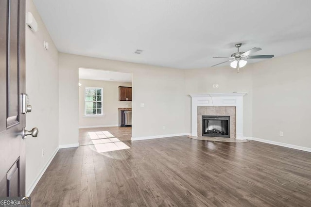 unfurnished living room with a tile fireplace, ceiling fan, and dark hardwood / wood-style floors