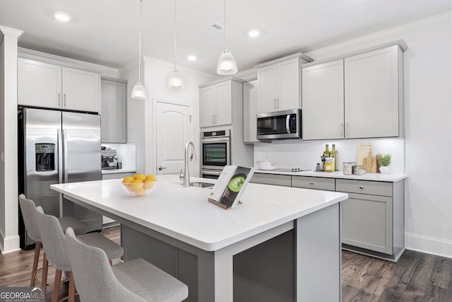 kitchen with stainless steel appliances, hanging light fixtures, a center island with sink, and sink