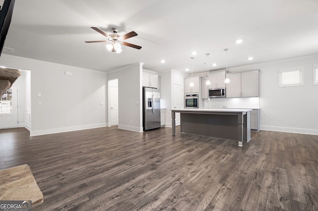 kitchen with appliances with stainless steel finishes, decorative light fixtures, a kitchen island with sink, and ornamental molding