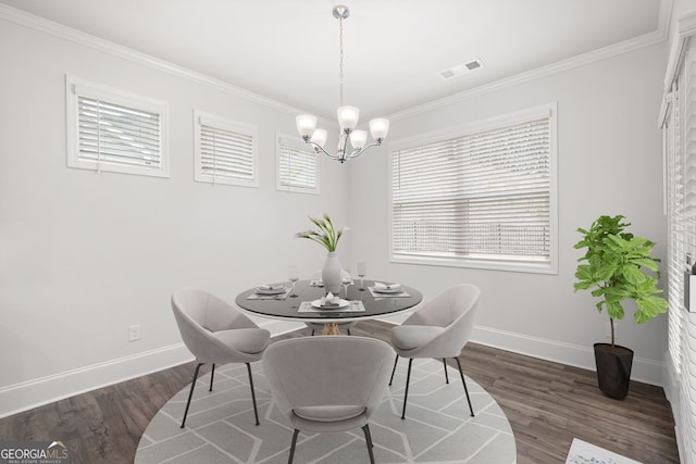 dining space with ornamental molding, dark wood-type flooring, and an inviting chandelier