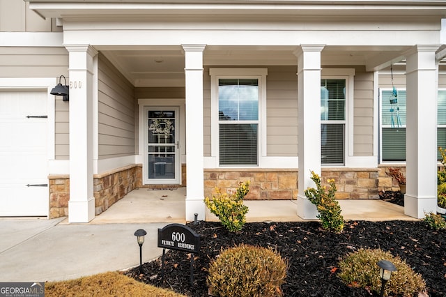 doorway to property featuring covered porch and a garage