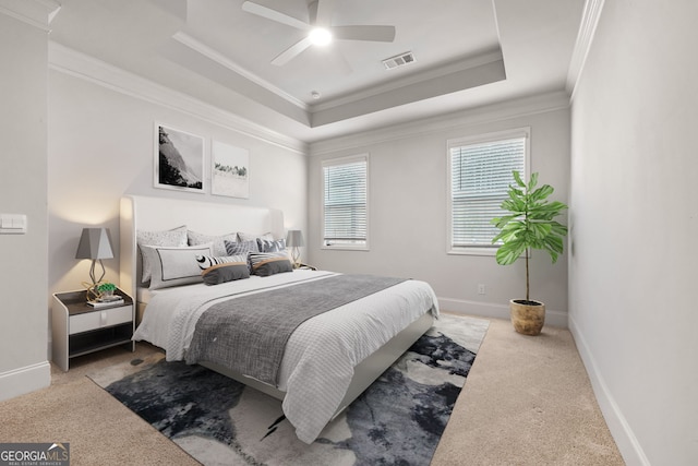 bedroom with a raised ceiling, ceiling fan, light colored carpet, and ornamental molding