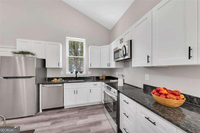 kitchen featuring lofted ceiling, sink, appliances with stainless steel finishes, light hardwood / wood-style floors, and white cabinetry