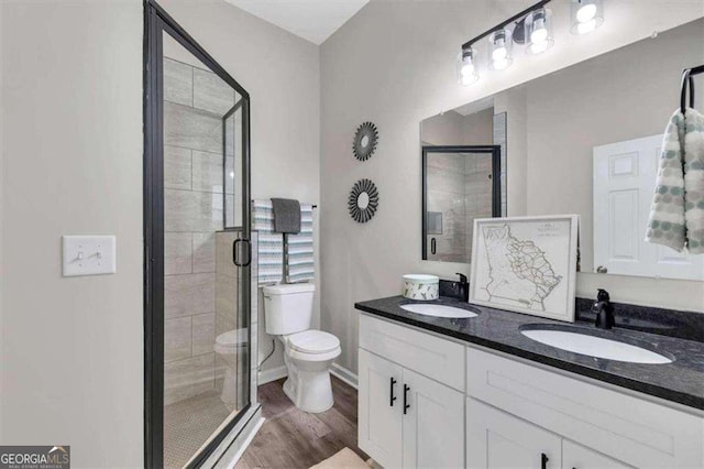 bathroom featuring wood-type flooring, vanity, toilet, and a shower with door