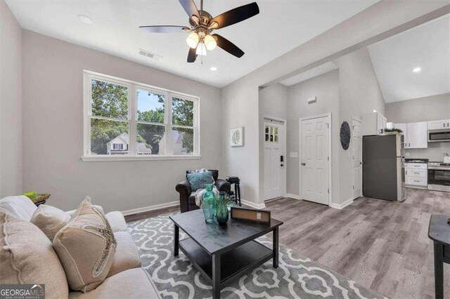 living room featuring ceiling fan, light hardwood / wood-style flooring, and lofted ceiling