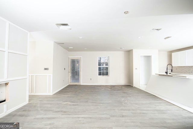 unfurnished living room with light hardwood / wood-style flooring and sink