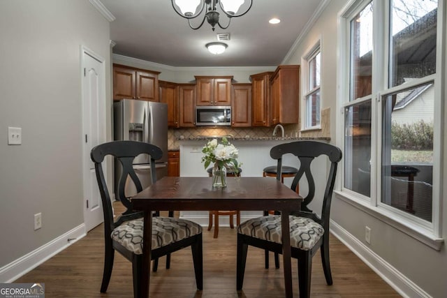 dining space featuring ornamental molding, an inviting chandelier, dark wood-type flooring, and sink