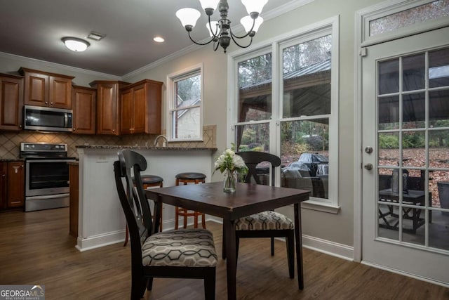 dining area with crown molding, dark wood-type flooring, and an inviting chandelier