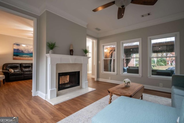 living room with a fireplace, hardwood / wood-style flooring, ceiling fan, and ornamental molding