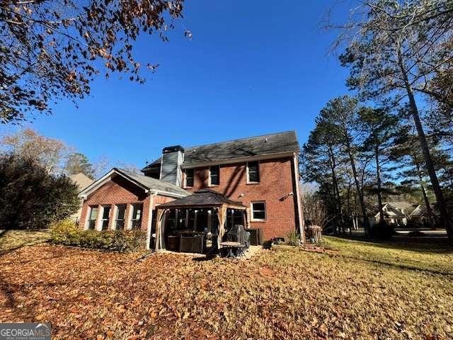 rear view of property with a gazebo and a lawn