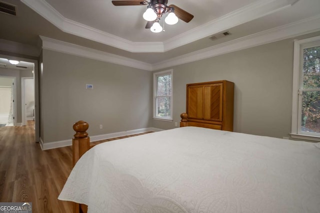 bedroom with a raised ceiling, ceiling fan, hardwood / wood-style flooring, and ornamental molding