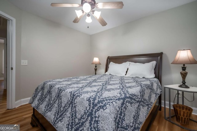 bedroom with dark hardwood / wood-style flooring and ceiling fan