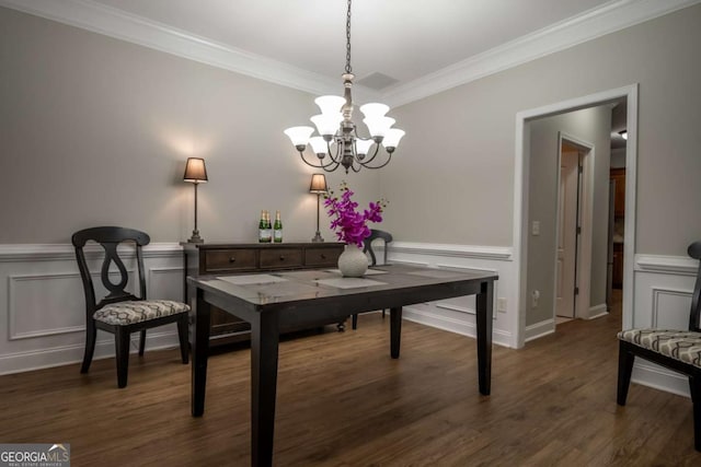 dining space with dark hardwood / wood-style floors, ornamental molding, and an inviting chandelier