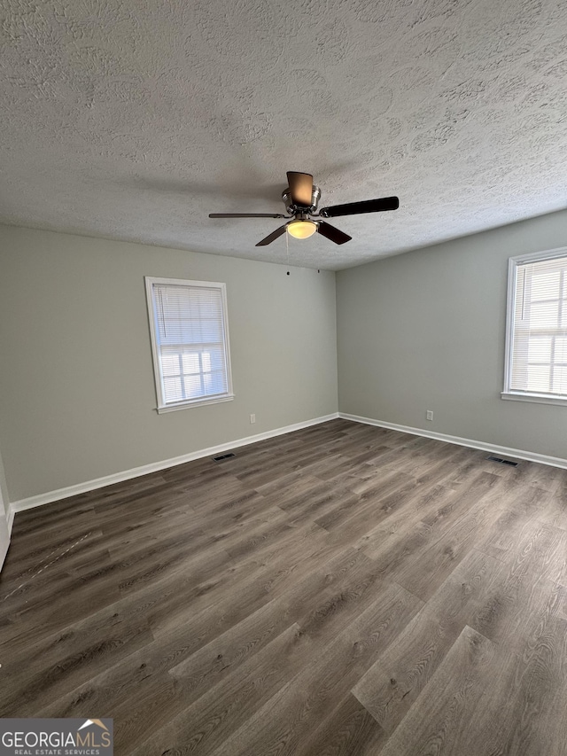 spare room featuring a textured ceiling, ceiling fan, and dark wood-type flooring